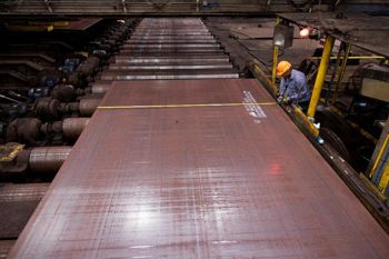 Hombre con un casco amarillo trabajando en una placa de acero
